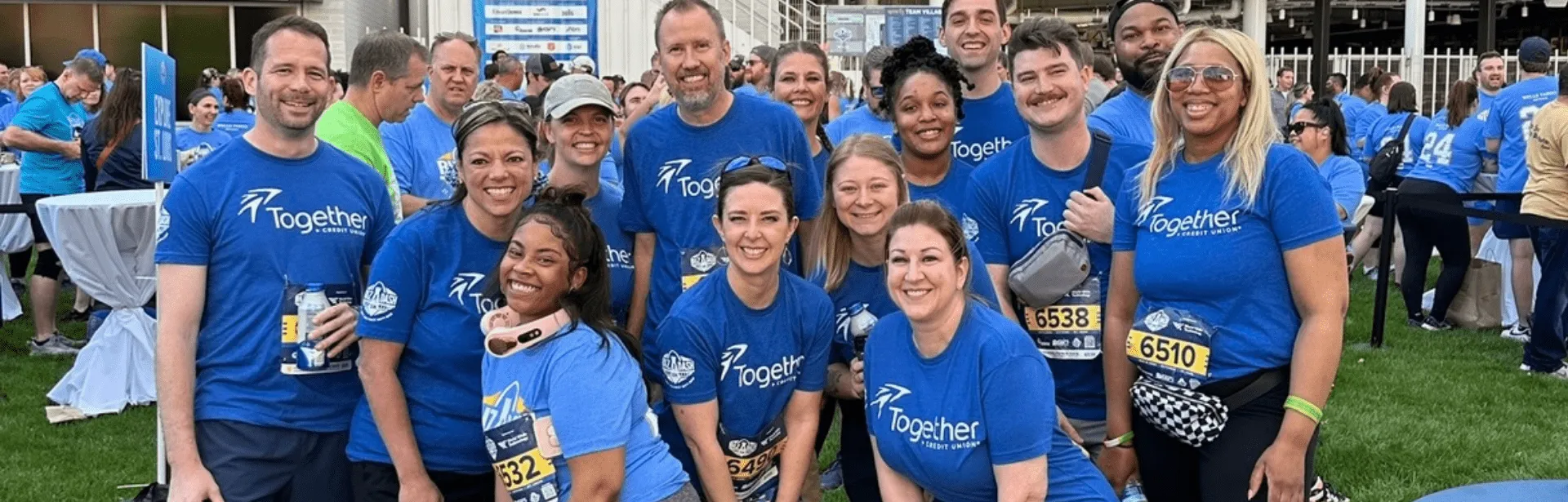 Several people standing together wearing blue t-shirts with the Together Credit Union logo.