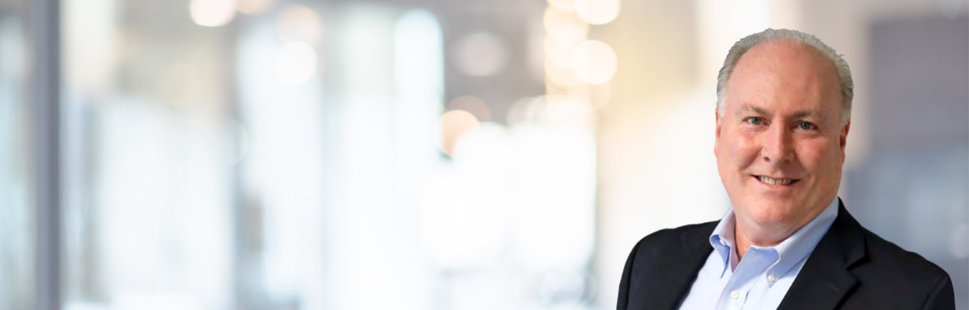 CEO Bob McKay smiles in front of well-lit office
