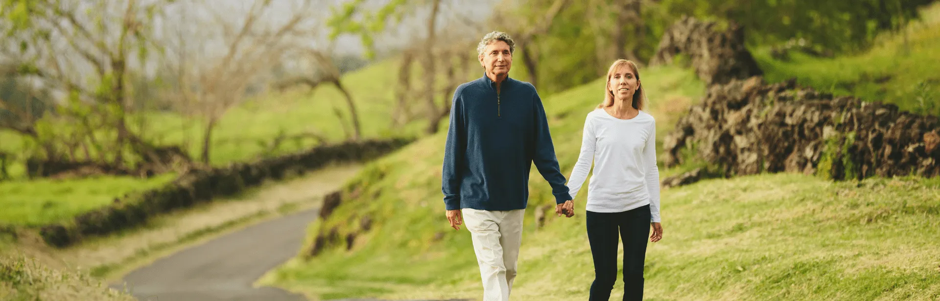 A couple holding hands and walking in a park.